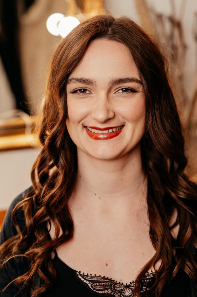 Lächelnde Frau bei Boudoir-Shooting in warmem Licht - Dein Boudoir Frau mit lockigem Haar und rotem Lippenstift beim Boudoir-Shooting.