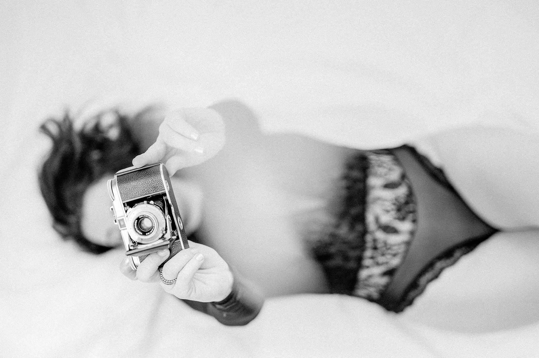 Frau in weißer Unterwäsche beim Boudoir-Shooting, entspannt und glücklich.