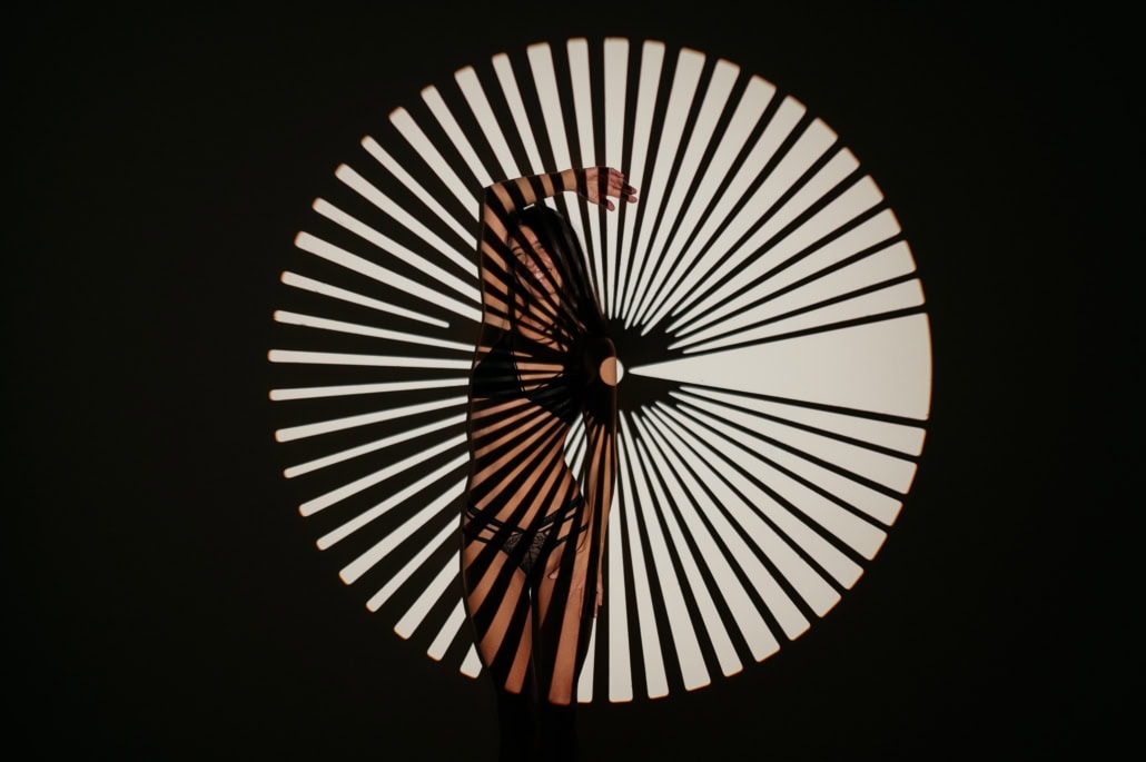 Künstlerische Darstellung eines Tänzers vor einem kreisförmigen Lichtmuster, das Schatten und Kontur.