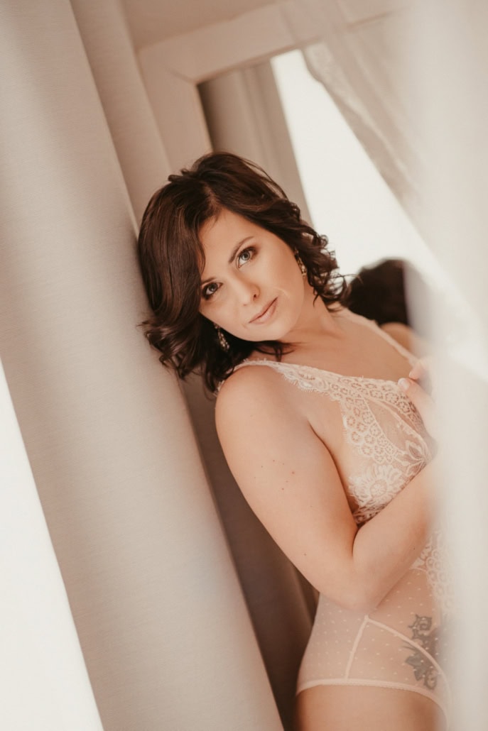 Sanfte Boudoir-Fotografie einer Frau in Spitze, entspannt und sinnlich. - Dein Boudoir Entspannte Frau in Spitze-Boudoir-Lingerie lehnt an der Wand, sinnliche Atmosphäre.