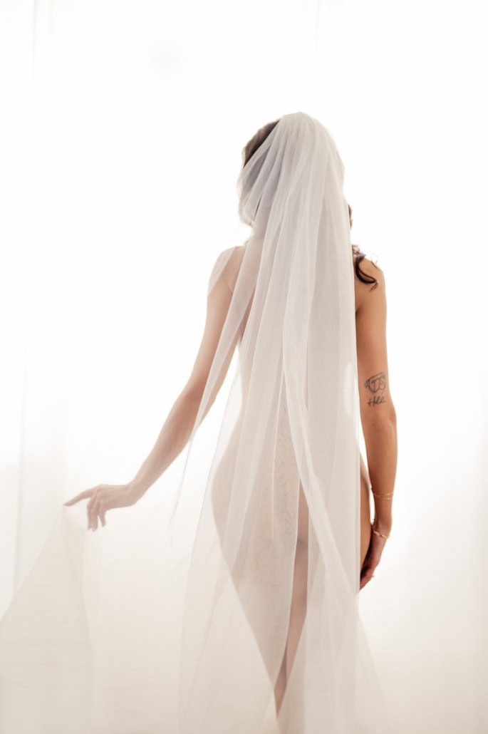 Elegantes Boudoir-Foto mit Schleier und zarter Pose - Dein Boudoir Schleier bedeckt den Körper einer Frau bei einem Boudoir-Shooting, sanftes Licht schafft eine sinnli.